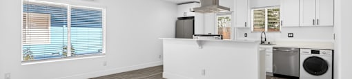 A kitchen with white cabinets and a wooden floor.