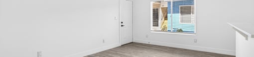 A room with wooden flooring and a window with blinds.