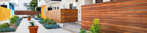 A row of modern houses with wooden fences and a concrete walkway.