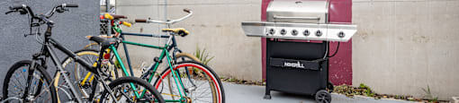 two bikes parked next to a wall with a grill
