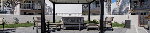 a patio with a couch and chairs under a gazebo