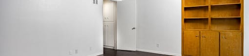 a living room with white walls and wood floors and a bookshelf