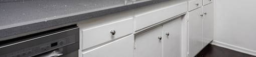 an empty kitchen with white cabinets and a sink