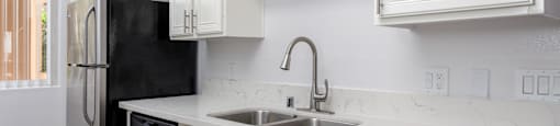 a kitchen with white cabinets and a sink and a refrigerator