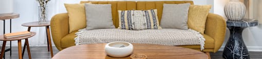 a living room with a yellow couch and a wooden table