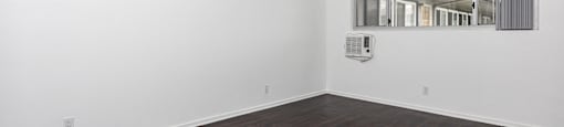 an empty room with white walls and wood floors and a window