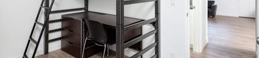 A black bunk bed with a desk underneath it in a room.
