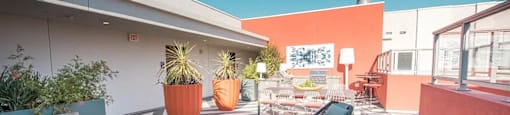 A patio with a couch, chairs, and a table with a blue pot on it.