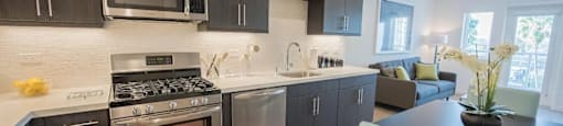 A modern kitchen with dark wood cabinets and stainless steel appliances.