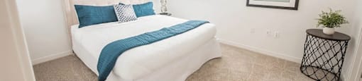 A bedroom with a white bed and a blue pillow.
