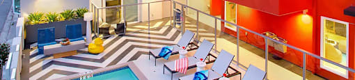 A swimming pool is surrounded by lounge chairs in a courtyard.