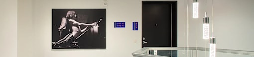 A hallway with a glass railing and a picture of a person playing guitar on the wall.