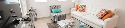 A modern living room with a white couch and a glass coffee table.