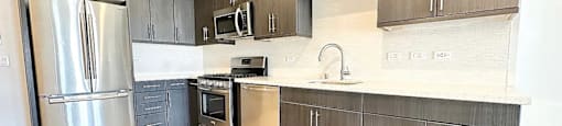 A kitchen with wooden floors and a stainless steel refrigerator.