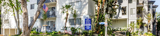 a white apartment building with palm trees and a blue sign