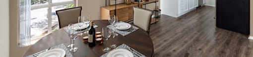 A dining room with a table set for two with a view of a backyard.