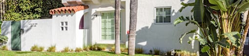 the exterior of a white house with palm trees
