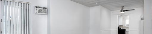 an empty living room with white walls and a ceiling fan