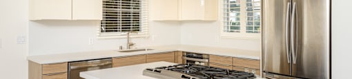 a kitchen with white counter tops and a stainless steel refrigerator