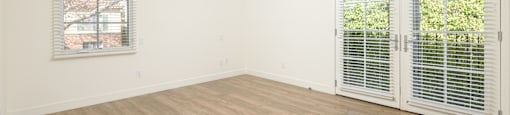 a living room with white walls and wood floors and a window