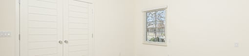 a bedroom with white walls and wood floors and a closet