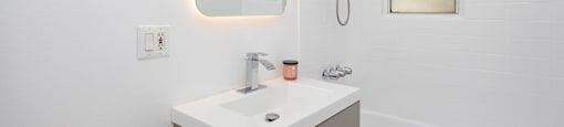 a bathroom with white walls and a white sink with a mirror above it