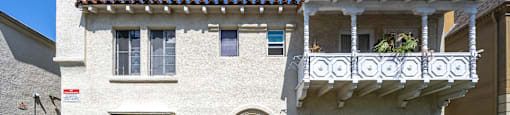a white house with a balcony and a green lawn