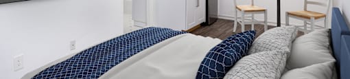 a bedroom with a bed and a kitchen with a table and chairs