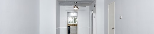 an empty living room with white walls and a ceiling fan