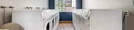 a laundry room with white washers and dryers