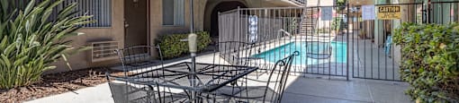 a patio with a table and chairs and a pool in the background