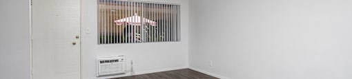 an empty living room with white walls and wood flooring