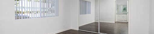 an empty living room with white walls and wood flooring and a sliding glass door