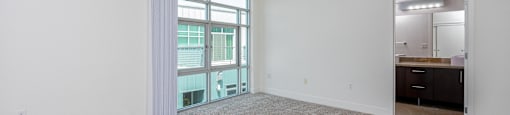an empty living room with white walls and carpeting and a window