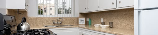 a kitchen with white cabinets and a stove and a sink
