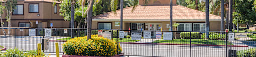 a building with a fence and palm trees in front of it