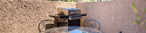 a patio with a table and chairs and a grill