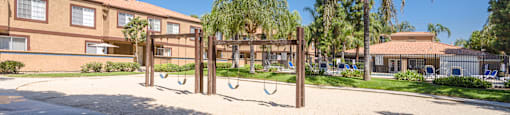 a playground in front of a school with trees and a building