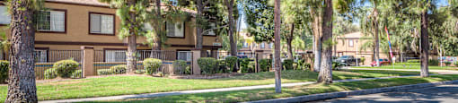 exterior view of apartments with trees and grass and a street