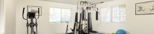 a gym with exercise equipment in the corner of a room