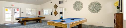 two pool tables in a community room with a blue table