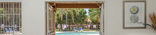 a view of a pool from a living room with a door open to a backyard
