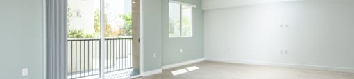 an empty living room with sliding glass doors to a balcony