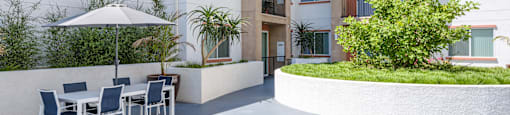 a patio with a table and chairs in front of an apartment building
