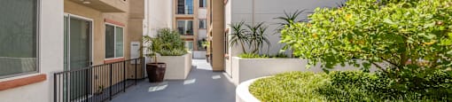 a corridor with buildings and plants on both sides and a blue sky