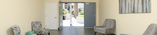 a waiting room with three chairs and a door to a lobby