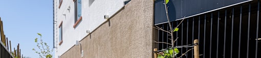 the side of a building with a fence and a sidewalk