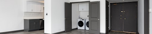 an empty living room with a washer and dryer in it and grey doors