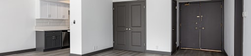 the living room and kitchen of an empty apartment with black doors and white walls