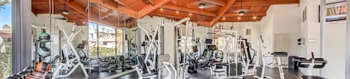 a gym with a wooden ceiling and weights on the floor